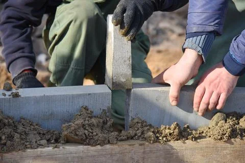 A worker puts a concrete wedge, installing concrete curbs in the cement. Stock Photos