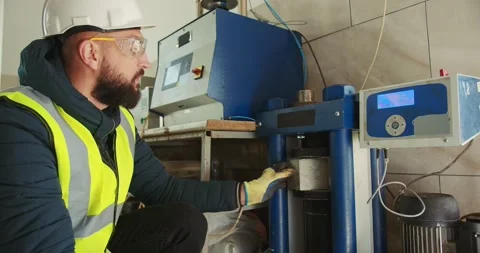 The worker puts a cube of concrete under the press for compressive strength test Video stock 277595848