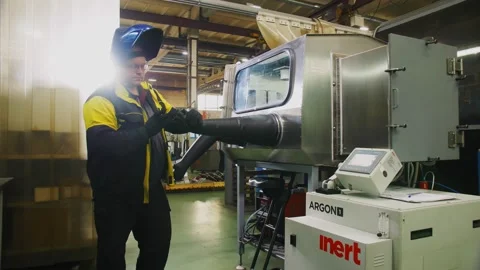 Worker puts hands into gloves of de-powdering enclosure 库存影片 137022853