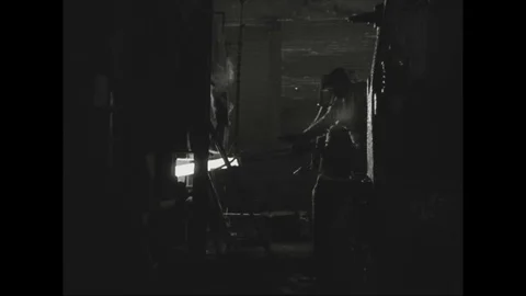 Worker puts hot rod on hammering machine to give shape in steel mill - 1938-1939 Stock Footage 103597657