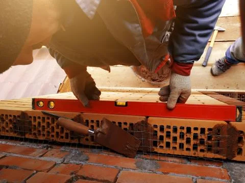 The worker puts the level on the silicate facade brick. 스톡 사진