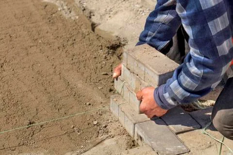 A worker puts on a nylon cord for the subsequent laying of paving slabs on th Stock Photos