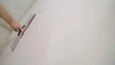 Worker puts putty on the tool. Close-up of a woman's hand with a metal spatul Foto stock