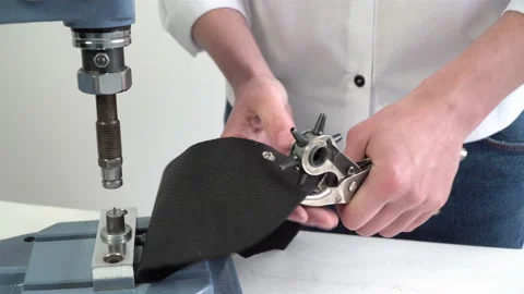A worker puts rivets on a leather product by a press machine 스톡 동영상 150220935