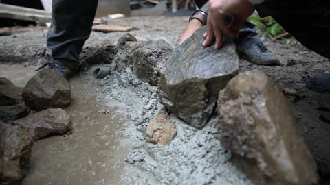Worker puts rock into fresh concrete Stock Footage 158974677