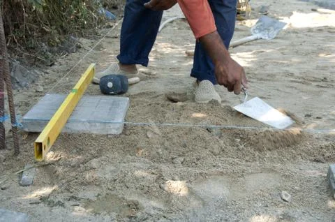 Worker puts sidewalk tiles Stock Photos