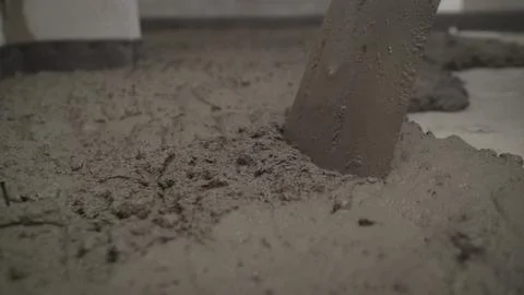 Worker puts a solution with a shovel on the floor. Worker levels the floor in Stock Photos