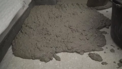 Worker puts a solution with a shovel on the floor. Worker levels the floor in Stock Photos