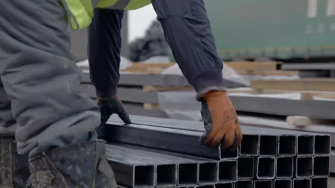 Worker puts square hollow section on stack in yard Vídeo Stock 255295834