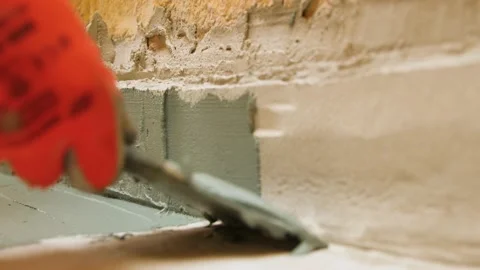 A  worker puts a trowel on the floor of plastering a wall with a floor. Video stock 199837390