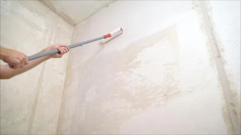 Worker puts a wall with a roller. A man uses a roller to apply wallpaper glue Stock Photos