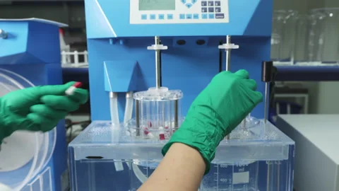 Worker puts the White-Red pills inside of the Containers in medical Laboratory Stock Footage 158239214