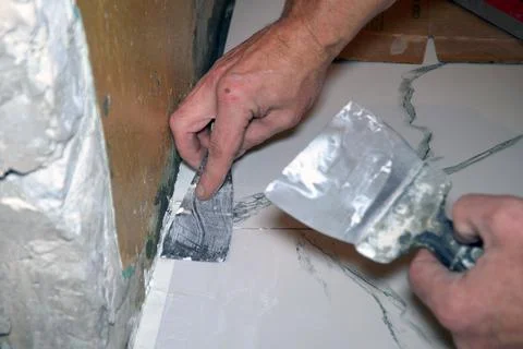 A worker putsty on the floor when laying ceramic floor tiles Stock Photos
