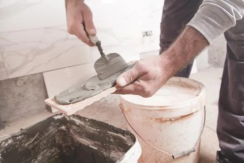 Worker putting adhesive to the tile. Stock Photos