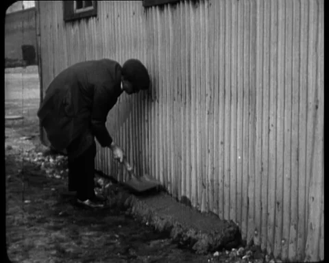 A worker putting cement around the iron fence, rat menace, 1925 Stock Footage 131081691