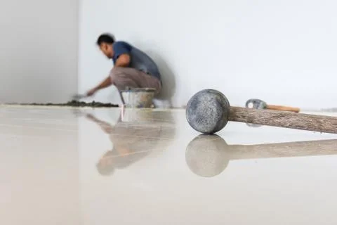 Worker putting ceramist tile on the floor. Professional ceramist is laying ce Stock-Fotos
