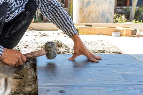 Worker putting ceramist tile on the floor. Professional ceramist is laying ce Stock Photos