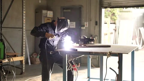 Worker putting helmet down and starting welding Stock Footage 241818209