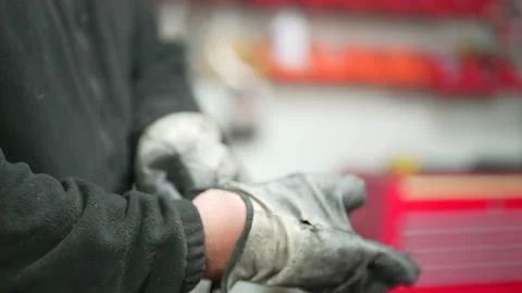 Worker putting on safety gloves in a clean and organized workshop Stock Footage 308829071