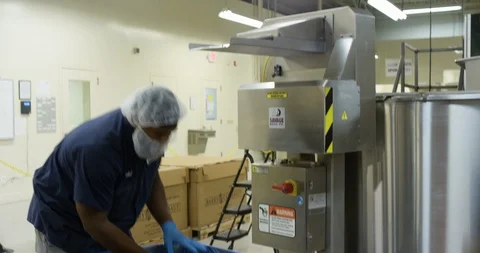 Worker putting slabs of chocolate in a machine in a chocolate factory Stock Footage 103999480