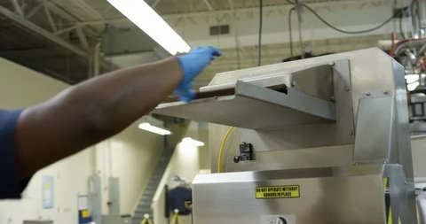 Worker putting slabs of chocolate in a machine in a chocolate factory Stock Footage 103999618