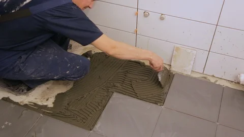 Worker putting tile glue on floor Stock Footage 128415942