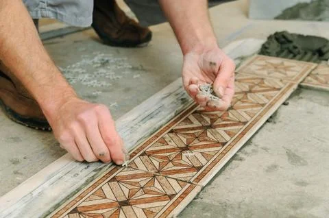 Worker putting tiles on the floor. Stock Photos