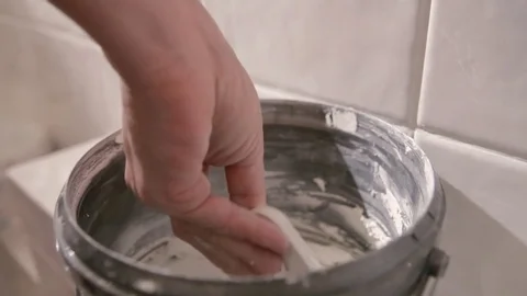 Worker putting tiles on the wall in the bathroom. His hands are placing the tile Stock Footage 76493319