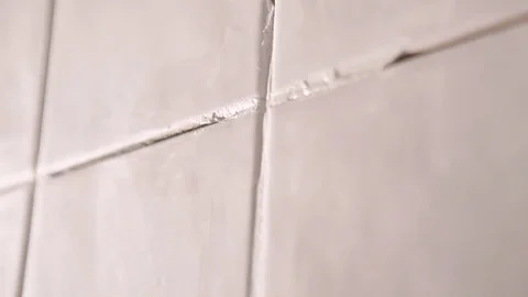 Worker putting tiles on the wall in the bathroom. His hands are placing the tile Video stock 76498621