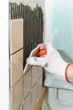 Worker  putting  tiles on the wall in the kitchen. Stock Photos