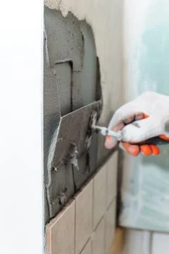Worker  putting  tiles on the wall in the kitchen. Stock Photos