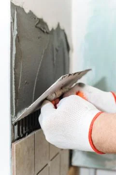 Worker  putting  tiles on the wall in the kitchen. Stock Photos