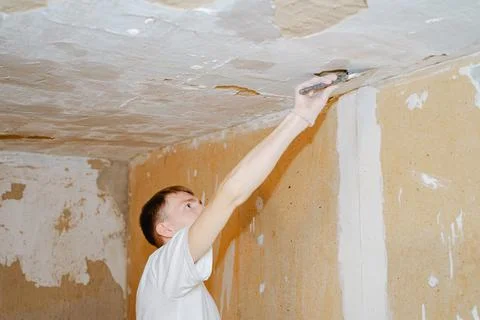Worker puttying holes in the ceiling Stock Photos