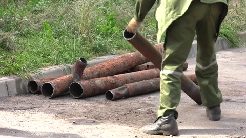 A worker raises an old rusty pipe from asphalt. Pipe close up Video stock 100553146