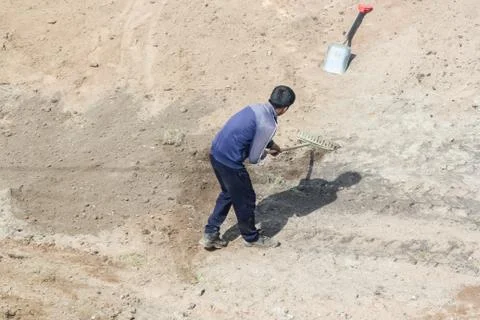Worker with a rake on the layout. Stock Photos
