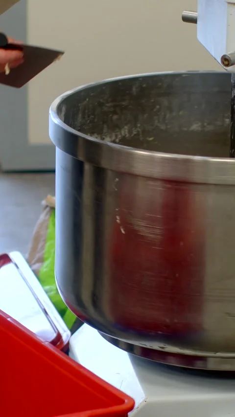 Worker reaching into large stainless steel mixing bowl in bakery prep, with Stock Footage 344570541