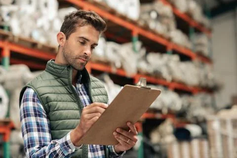 Worker reading an inventory while standing on a warehouse floor Stock Photos