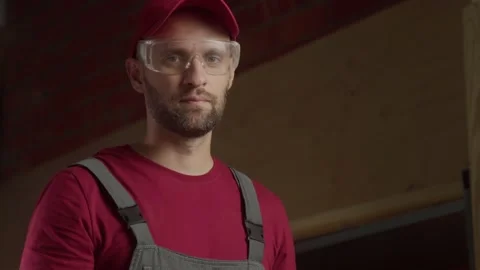 A worker in a red cap and overalls is preparing to complete a task in the Stock Footage 281673571