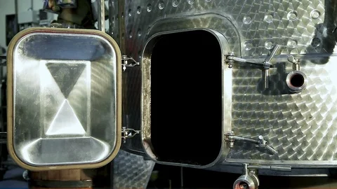 Worker in a red jacket closes the door of the wine tank made of stainless steel Stock Footage 99103731
