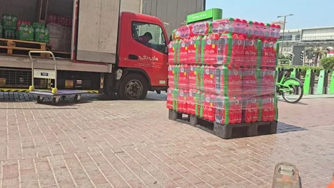 A worker in a red shirt wraps a pallet of bottled water outside a truck Stock Footage 311884441