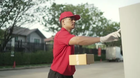 Worker red uniform is holding a parcel box  ringing the bell for the recipient. Stock Footage 243070689