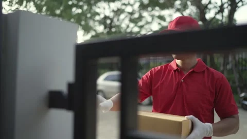 Worker red uniform is holding a parcel box  ringing the bell for the recipient. Stock Footage 243070700