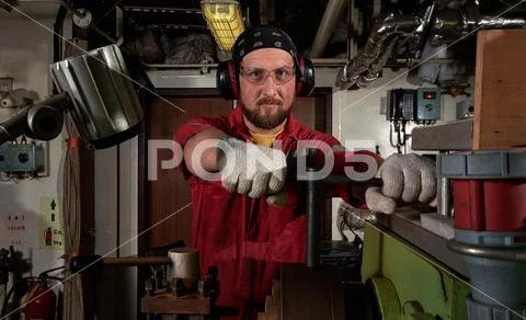 Worker in red uniform operating in manual lathe in metal big workshop with da Stock Photos
