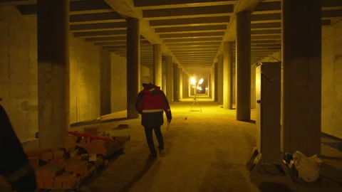Worker in reflective jacket walks between massive columns Stock Footage 316098454