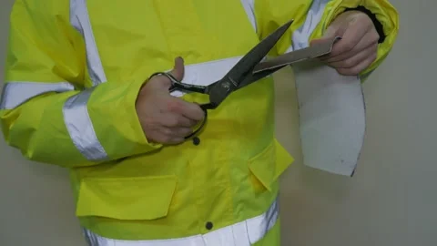 A worker in a reflective uniform cuts the fabric Stock Footage 220433561