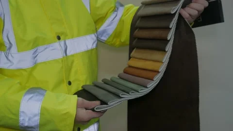 Worker in reflective uniform selects fabric Stock Footage 220433491