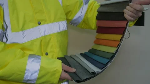 Worker in reflective uniform selects fabric Stock-Footage 220433560