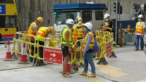 Worker in reflective vest with drill repairing street during roadwo Stock Footage 157536062