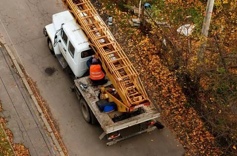 Worker in reflective vest fixing a mobile crane on a truck in autumn, const.. Stock Photos