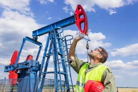 Worker refreshing after hard work on oil pump Stock Photos